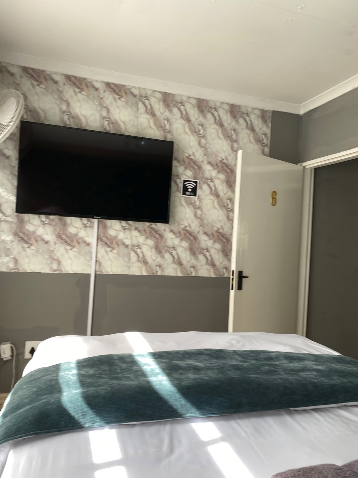 Room 6 flat-screen TV on marble feature wall with Wi-Fi sign