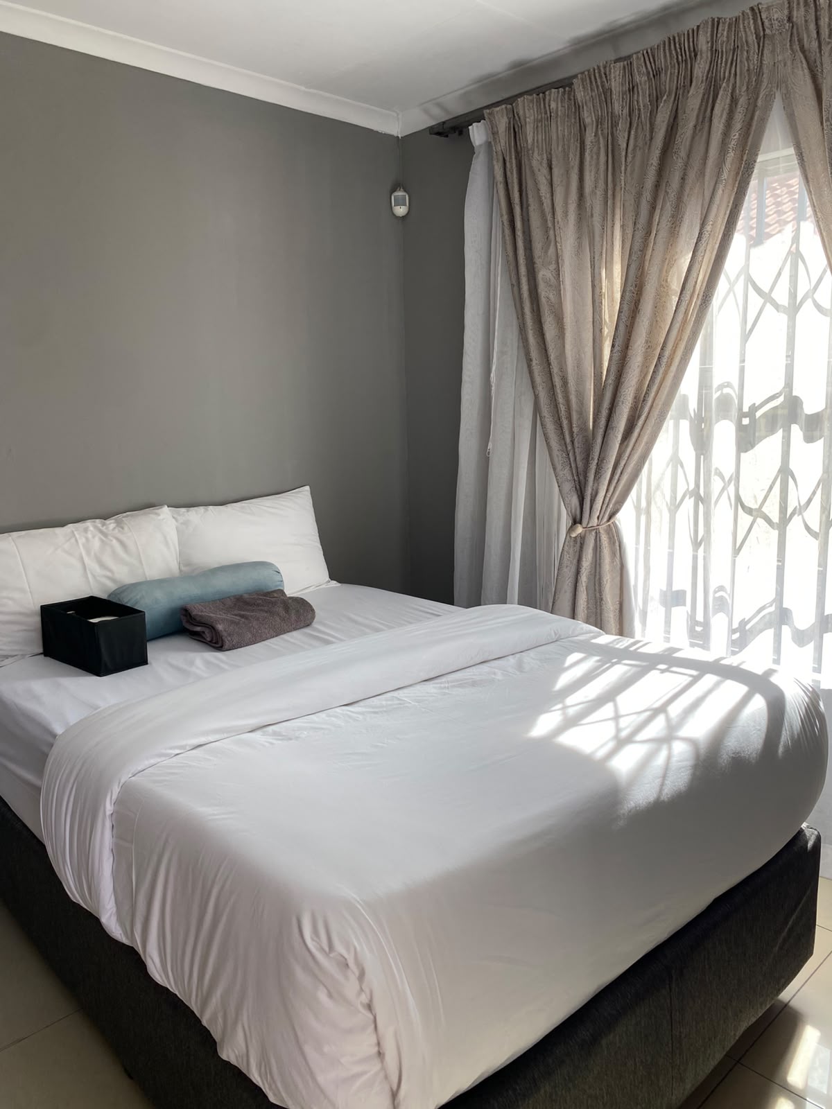 Room 6 double bed with crisp white linen and fresh towels at Bahumi Guesthouse 2